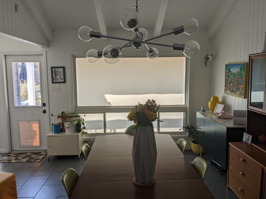 Inside picture of a dining room with white exterior roller blinds covering the window. 